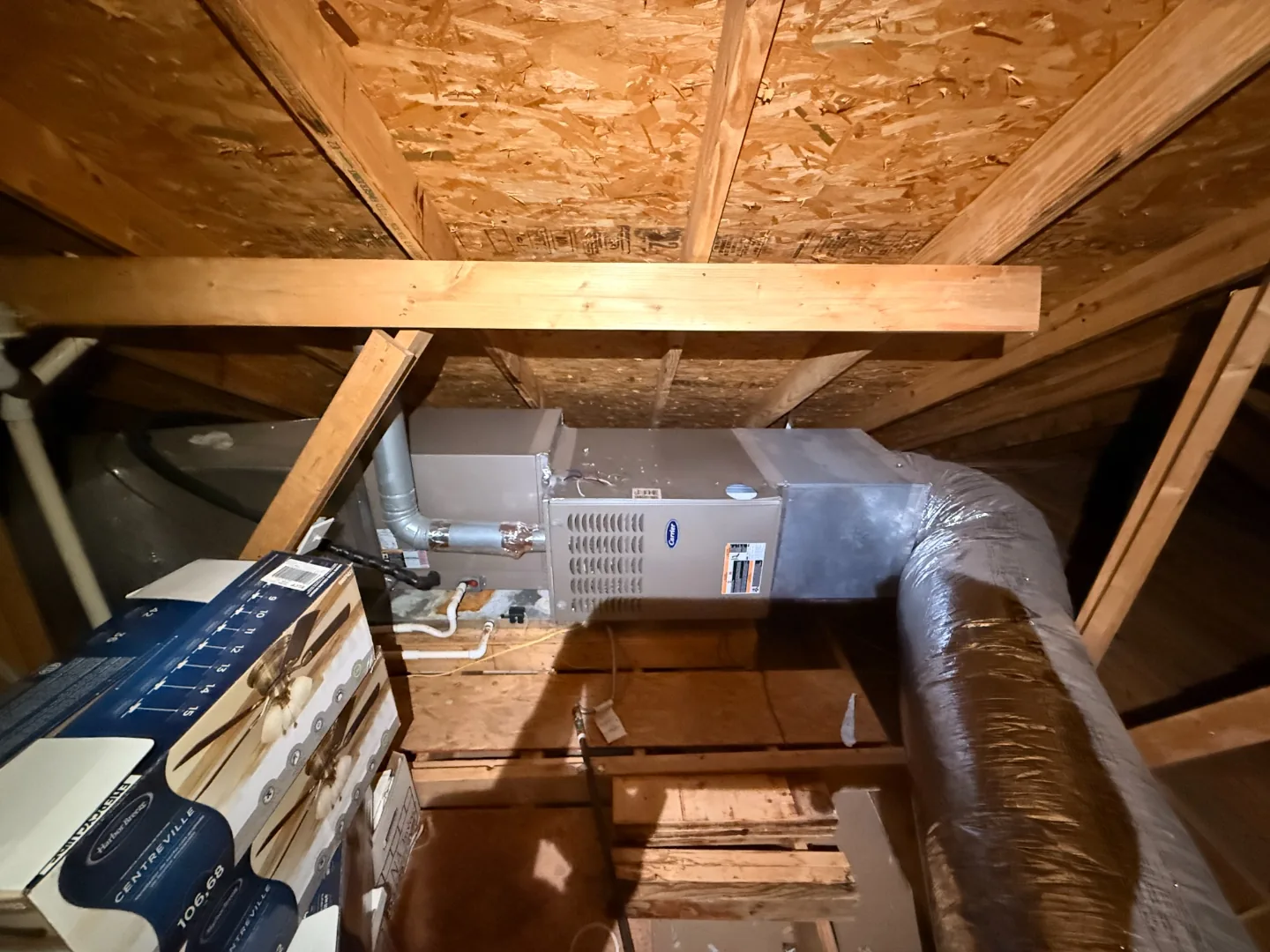 Horizontal gas furnace and air handler installed in an attic among wood rafters, with a metal flue pipe and insulated flex ducts